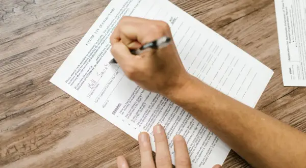 Osoba wypełnia formularz podatkowy, przygotowując się do złożenia dokumentów związanych z umowami o unikaniu podwójnego opodatkowania.