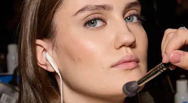Applicazione di un pennello per il trucco sul viso, forse per schiarire il fondotinta o sfumare il blush.