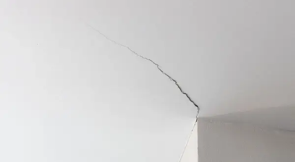 Fissure sur un plafond blanc, signe d'une trame de renovation nécessaire.
