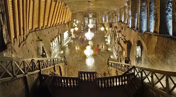 Wielka komora kopalni soli „Wieliczka” z kryształowymi żyrandolami i turystami. Opinie o tym miejscu są zachwycające.