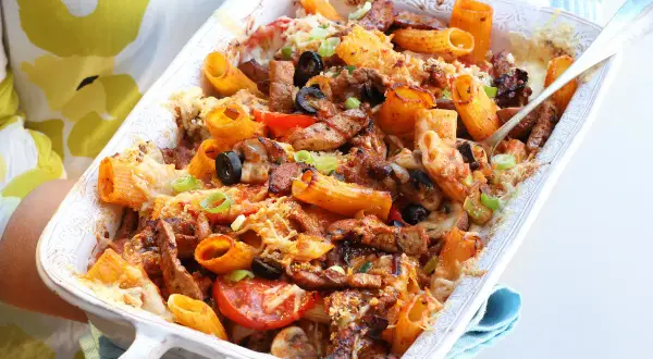 Pyszna zapiekanka gyros z makaronem, podana w białej brytfance, z widocznymi kawałkami mięsa, oliwek i pomidorów.