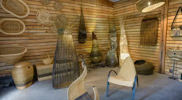 Atelier de vannerie. Des paniers, des luminaires et des sièges en osier, prêts à peindre de l'osier, décorent les murs en bois.