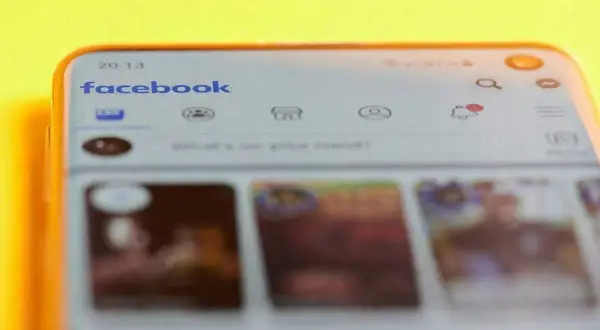Telefon z otwartą aplikacją Facebook. Widoczny pasek wyszukiwania i ikony powiadomień. Dowiedz się, jak znaleźć swoje relacje na Facebooku.