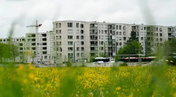 Bloki mieszkalne w budowie, z dźwigiem w tle. Obok droga z autobusami. Zastanawiasz się, ile zarabia deweloper na bloku?