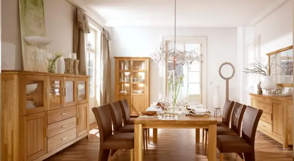 Elegancki salon w starym stylu aranżacje: drewniane meble, brązowe krzesła i stół nakryty do kolacji.