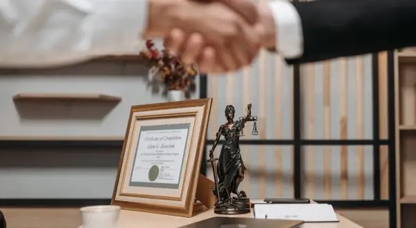 Uścisk dłoni prawników, certyfikat ukończenia i Statua Temidy. Dowiedz się, jak szybko się rozwieść, szukając profesjonalnej pomocy.