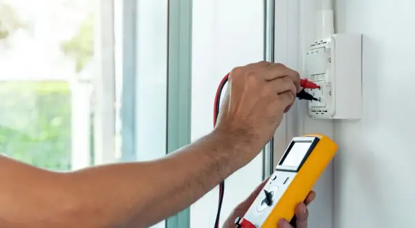 Elektryk wykonuje pomiar impedancji pętli zwarcia, używając miernika do sprawdzenia instalacji elektrycznej.