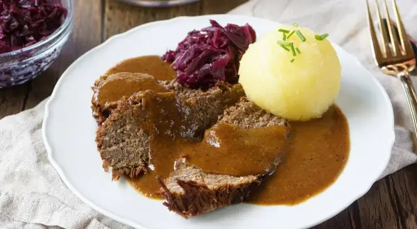 Sauerbraten rezept: Zarte Scheiben Braten in dunkler Sauce, serviert mit Rotkohl und Klößen. Ein Klassiker der deutschen Küche.