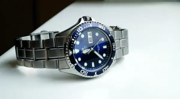 En blå dykarklocka, Orient Ray II, med ett silverfärgat armband ligger på en vit yta.