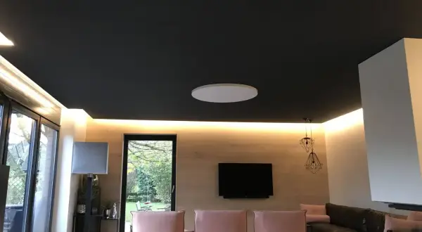 Nowoczesny salon z czarnym sufitem napinanym. Widać subtelne wady w postaci delikatnych zagnieceń na jego powierzchni.