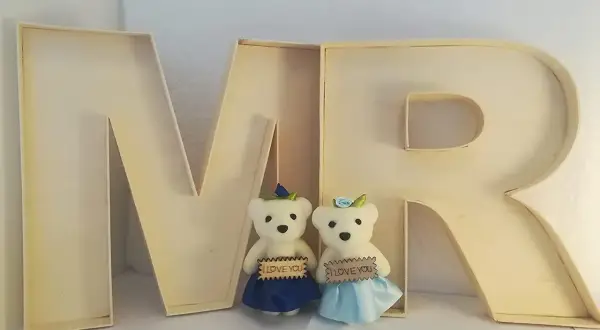 Deux oursons tiennent des pancartes "I LOVE YOU" devant une lettre creuse "MR".