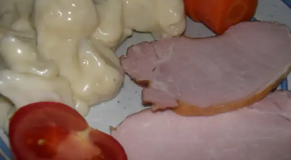 En tallrik med stuvad blomkål, skinka, en morot och en tomatklyfta. En klassisk svensk husmansrätt.