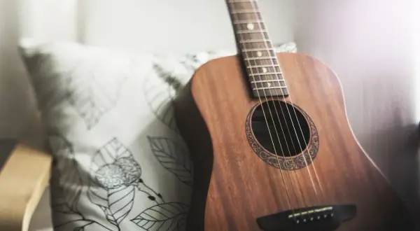 Akustyczna gitara obok poduszki z liśćmi. Idealna do grania harcerskie piosenki chwyty przy ognisku.