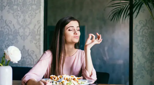 Frau genießt ihr Essen, als ob sie OMAD Fasten praktiziert und die einzige Mahlzeit des Tages zelebriert.
