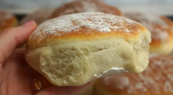 En hand håller en nybakad tekaka, pudrad med mjöl. Perfekt för ett enkelt tekakor recept.
