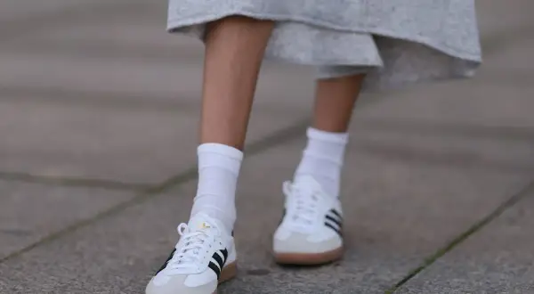 Białe Adidas Samba w stylizacjach z szarą spódnicą i białymi skarpetkami. Klasyka, która zawsze się obroni.
