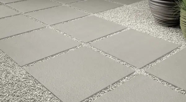 Posa a secco su ghiaia: lastre quadrate grigie alternate a ghiaietto bianco creano un percorso moderno e pulito.