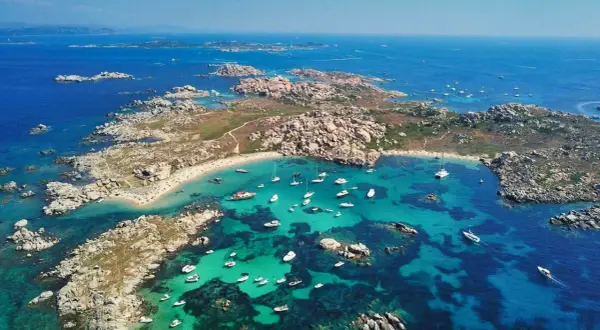 Vue aérienne d'une **excursion île Lavezzi** : eaux turquoise, plages de sable fin, rochers granitiques et nombreux bateaux au mouillage.