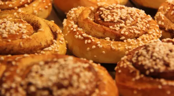 En närbild på nybakade kanelbullar, perfekta för kanelbullens dag. Strösslade med pärlsocker och kanel.