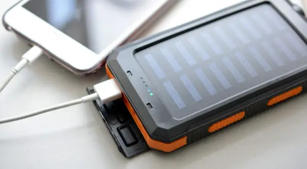 Ładowanie słuchawek bezprzewodowych ładowarką do telefonu jest możliwe, jeśli mają ten sam typ złącza. Na zdjęciu widać powerbank z panelem słonecznym ładujący telefon.