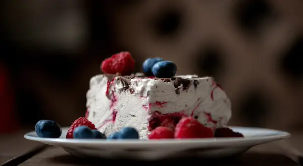 Ein Stück Eistorte mit Beeren und Schokostückchen, perfekt für ein einfaches Eistorte Rezept.