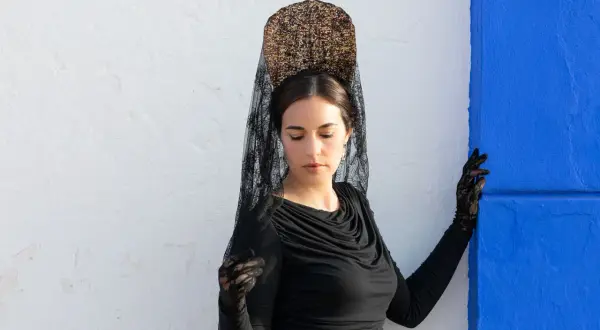 Mujer con peineta y mantilla negra, guantes de encaje, lista para una ocasión especial.