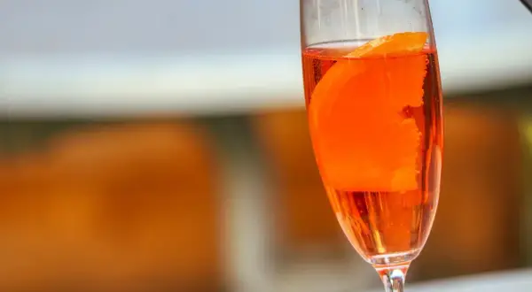 Orzeźwiający lillet drink z plasterkiem pomarańczy w kieliszku, gotowy na letnie popołudnie.