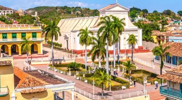 Plaza de Trinidad, Cuba. Un lugar perfecto para planear cuando viajar a Cuba, con su iglesia blanca, casas coloniales y palmeras.