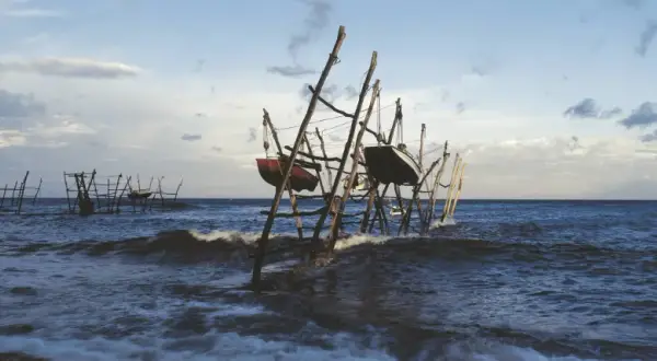 Barcas colgadas en estructuras de madera sobre el mar agitado, un paisaje evocador de lebeche en Rodalquilar.