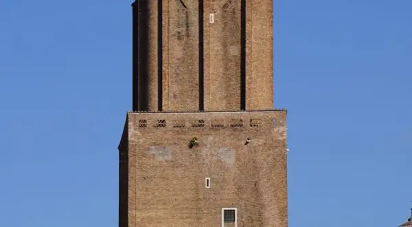 La torre delle Milizie, imponente struttura in mattoni, si staglia contro un cielo azzurro.