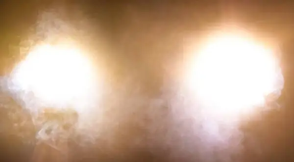 Deux halos lumineux, couleur feu de croisement, traversent une brume légère.