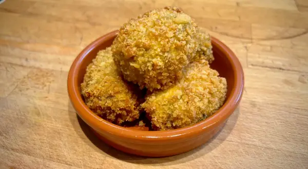 Goldbraune spanische Kroketten, knusprig paniert, in einer Tonschale. Ein leckeres spanische kroketten rezept zum Genießen.