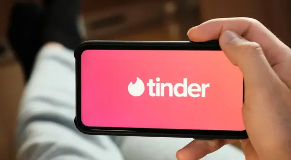 Dłoń trzyma smartfon z otwartą aplikacją Tinder.