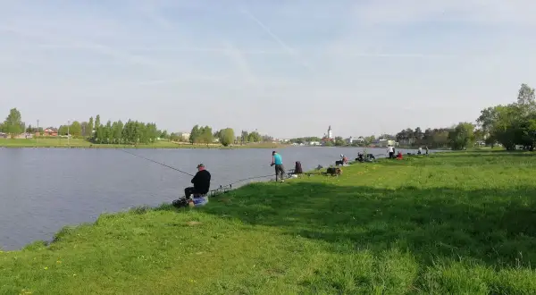 Wędkarze relaksują się nad wodą, łowiąc ryby na zalewie Stryków. Słoneczny dzień sprzyja wypoczynkowi.