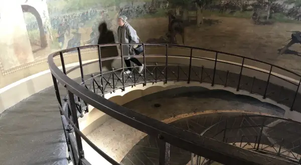 Una persona sale la scala a chiocciola all'interno della torre di San Martino, con un affresco di battaglia che decora le pareti.