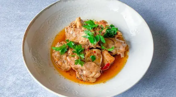Sabroso conejo en salmorejo, trozos de carne tierna bañados en una salsa rica y aromática, decorado con perejil fresco.