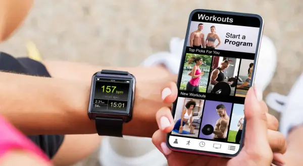 Une personne utilise son smartphone pour apprendre comment régler une montre connectée smartwatch, affichant des entraînements et des données de fitness.