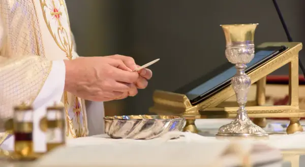 Kapłan trzyma opłatek, przygotowując się do Eucharystii. Co to jest Eucharystia? To sakrament.