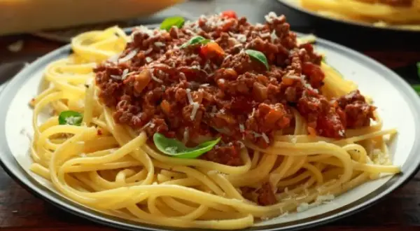 Pyszne spaghetti bolognese, idealne danie, gdy zastanawiasz się, co zrobić z makaronu spaghetti. Posypane parmezanem i listkami bazylii.
