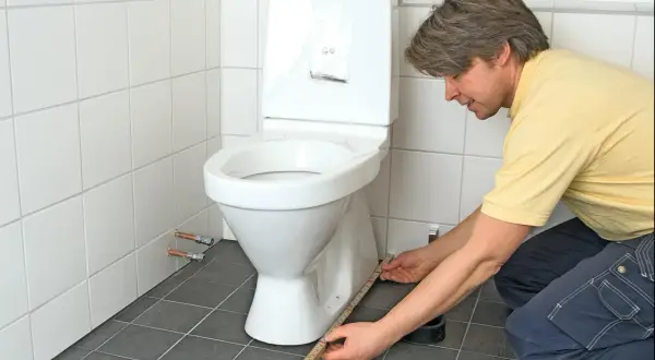 Man mäter för att limma toalettstol.