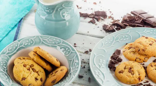 Schokoladenkekse, ein Krug Milch und zerbrochene Schokolade – perfekt für ein leckeres Cookies Rezept.