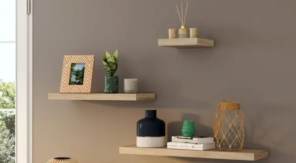 Trois étagères murales en bois clair décorées d'objets : cadre photo, plantes, bougies, vases, livres et diffuseur.