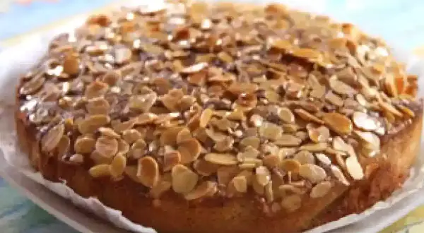 Gâteau aux amandes, doré et croustillant, garni de lamelles d'amandes grillées sur un glaçage brillant.