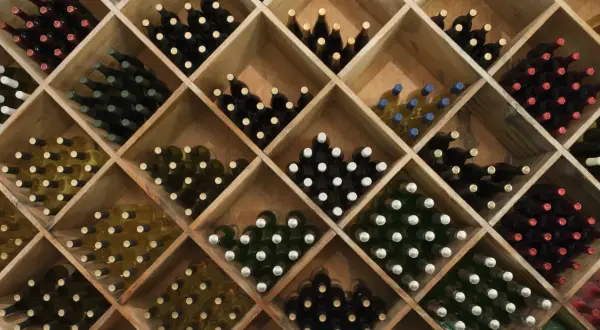 Weinregal mit vielen Flaschen Rotwein und Weißwein. Die Frage, wie lange kann man Rotwein lagern, wird hier durch die Vielfalt der Weine angedeutet.