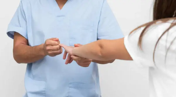 Fizjoterapeuta bada palec pacjentki. Gdy masz wybity palec, do jakiego lekarza się udać?