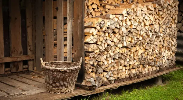 Ein Korb steht neben einem Holzstapel, bereit, das Holz im Ofen zu trocknen.