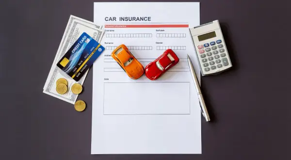 Documento di assicurazione auto, denaro, carte di credito e macchinina. È obbligatorio avere il certificato di assicurazione in auto.