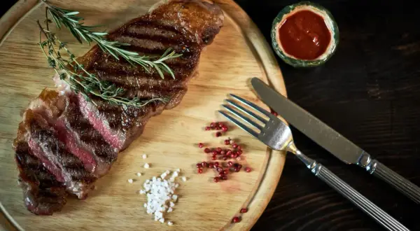 Succulenta bistecca di manzo, uno dei tanti tipi di bistecche di manzo, servita con rosmarino, sale grosso e pepe rosa.