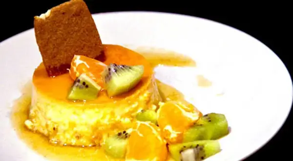 En krämig creme caramel med frukt och en kexbit. Perfekt för ett somrigt recept.