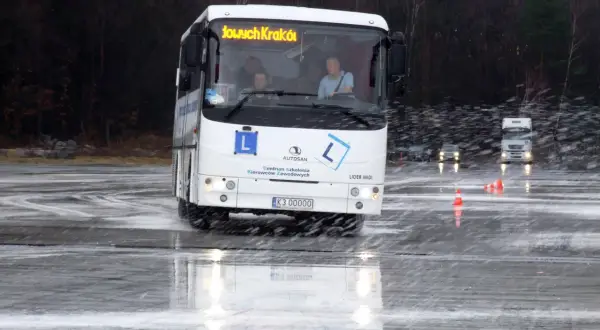 Autosan Lider Midi na mokrym placu manewrowym, z widocznymi kierowcami w kabinie.